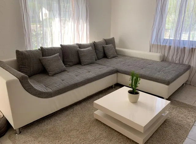 Aus der Polsterwerkstatt Egora: Das Ecksofa im Wohnraum: weisser Lederkorpus, graue Kissen, bodentiefer Aufbau (Ecksofa mit Ledersockel, Sofa neu beziehen)