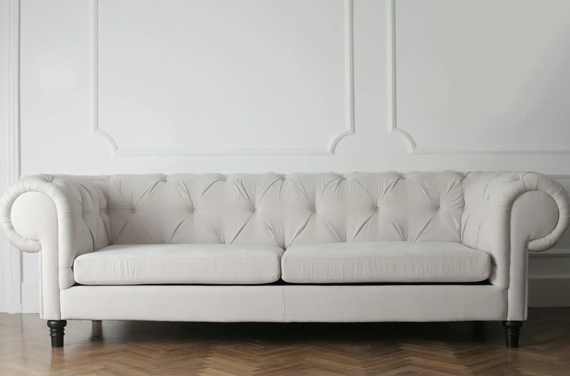 Massgefertigtes weisses Chesterfield-Sofa vor getäfelter Wand